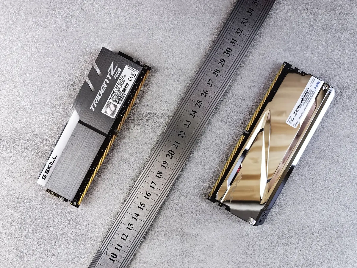 Close-up of computer memory modules and metal ruler placed on a textured gray surface.