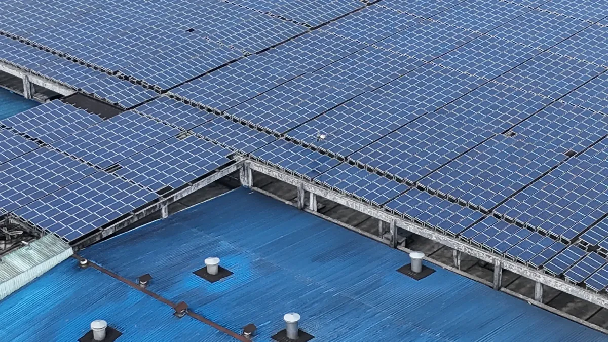 Aerial shot of solar panels installed on a blue industrial rooftop.